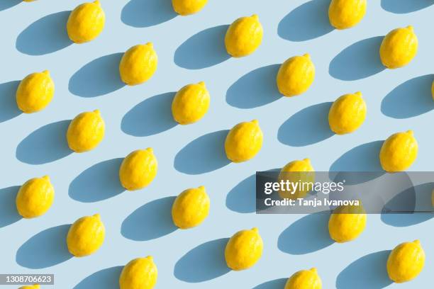 colorful fruit pattern of fresh yellow lemons on blue background with shadows. fruit concept. flat lay, top view. - lemon pattern photos et images de collection