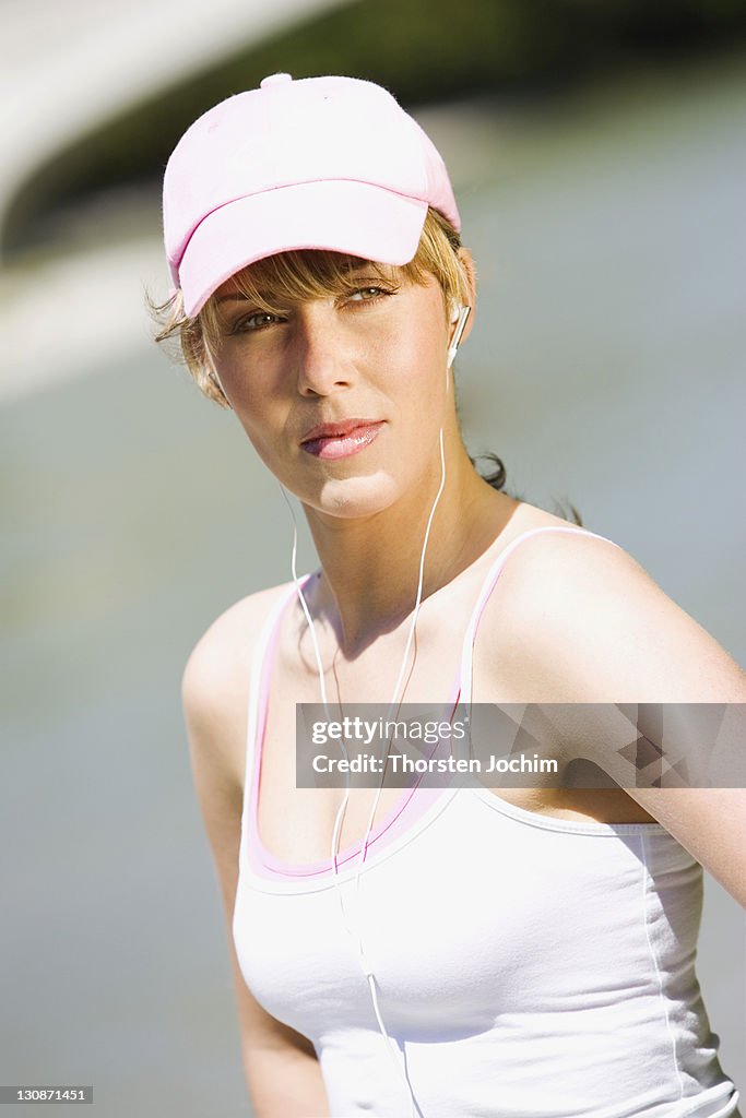 Young blond woman with white top, cap and earphones