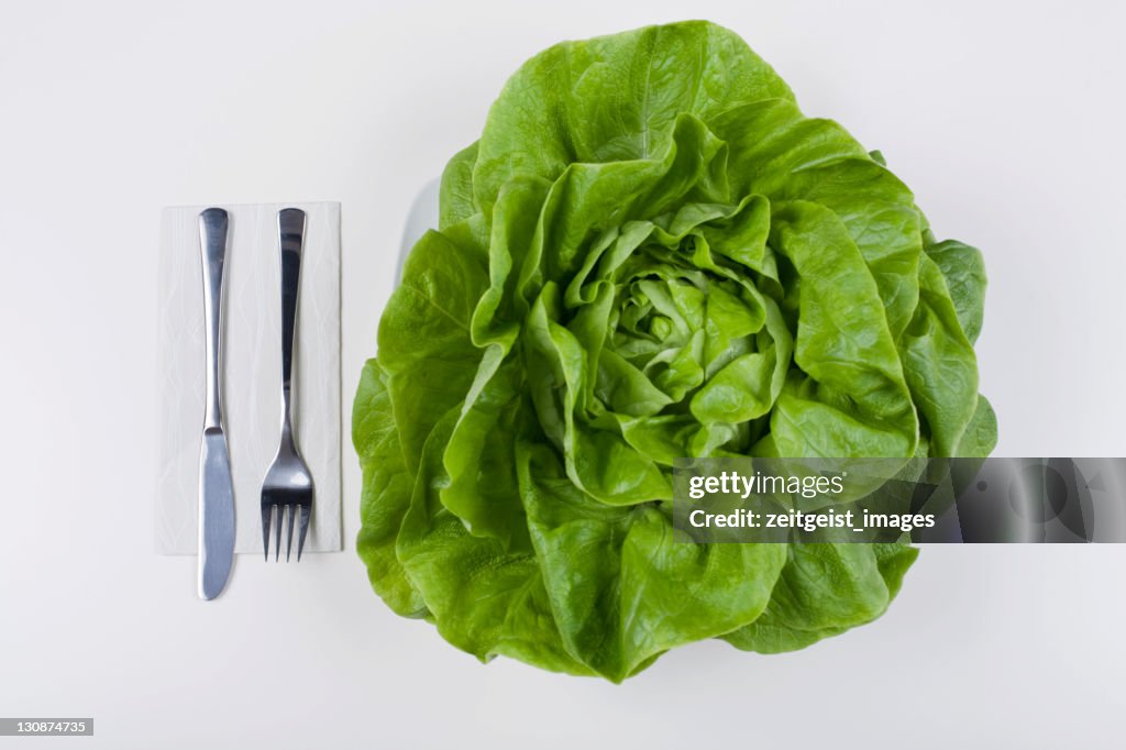 Head of lettuce on a plate, cutlery beside it