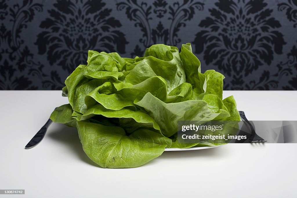 Head of lettuce on a plate, cutlery beside it