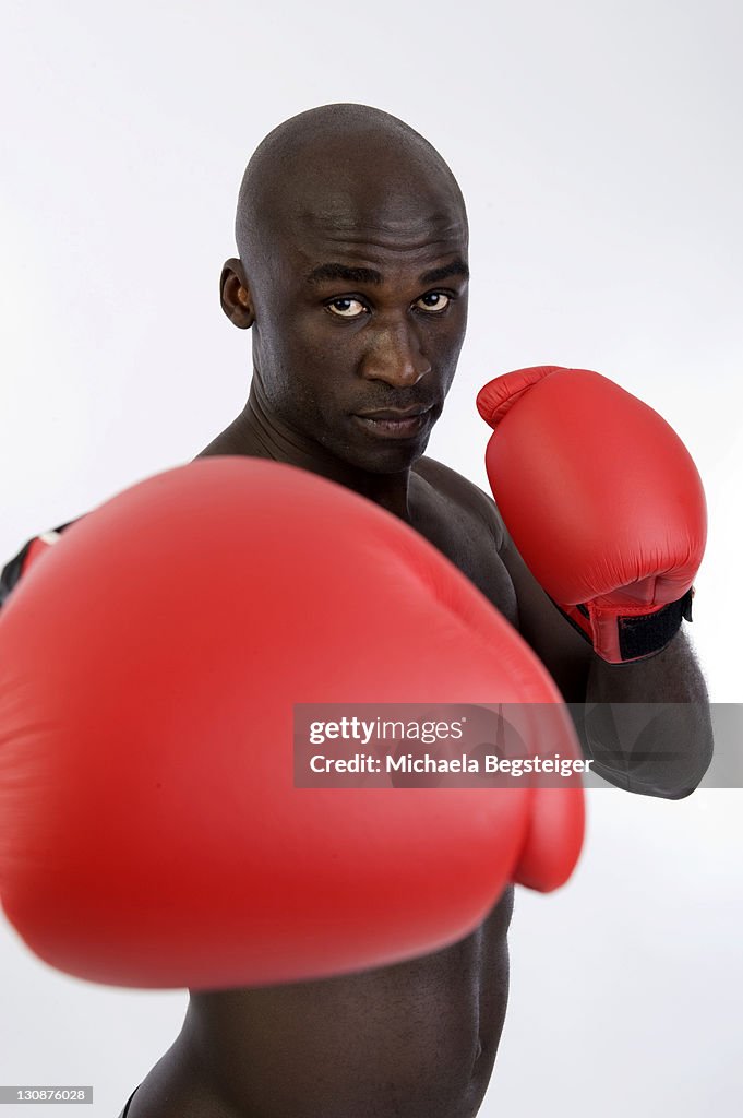 Dark-skinned, athletic man, 30, wearing boxing gloves
