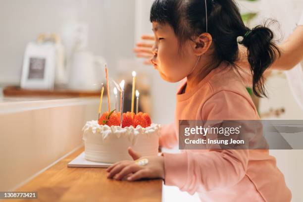 happy little girl blowing out the candles on her birthday cake - kid birthday cake stock pictures, royalty-free photos & images
