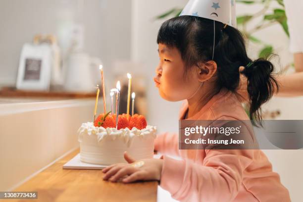 happy little girl blowing out the candles on her birthday cake - 韓国　スイーツ ストックフォトと画像