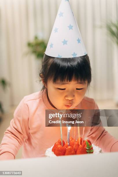 happy little girl blowing out the candles on her birthday cake - jb of south korean stockfoto's en -beelden