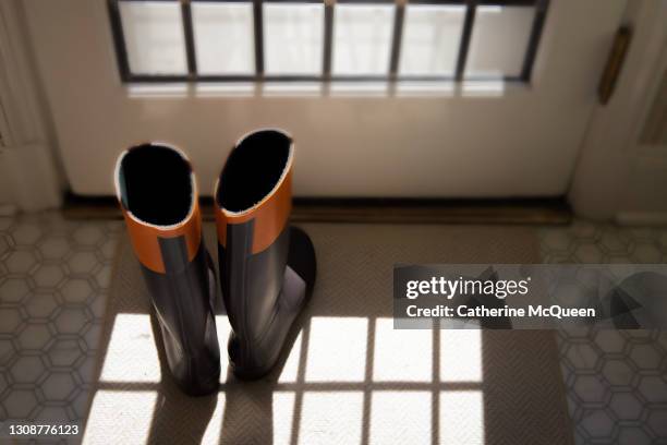 tall rubber rain boots by the sunroom door - rainy season stock-fotos und bilder