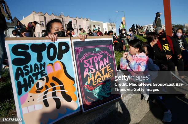 Annie Hong, of Oakland, holds signs during an anti-Asian hate vigil at Chinatown's Madison Park in downtown Oakland, Calif., on Tuesday, March 23,...
