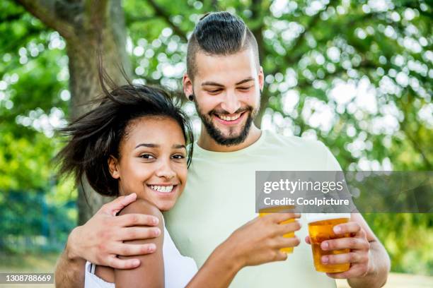 multiethnic couple drinking beer - biergarten stock-fotos und bilder