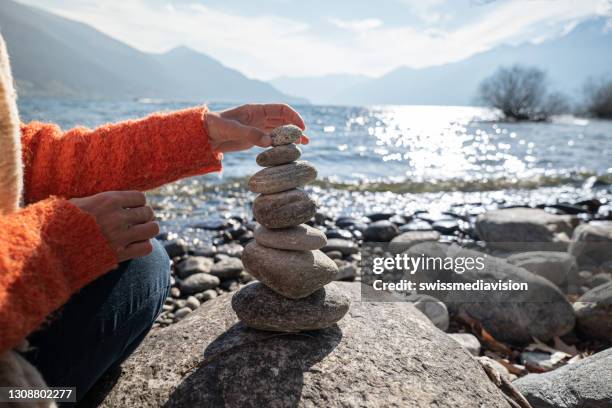 detalle de la persona apilando rocas junto al lago - manos de piedra fotografías e imágenes de stock