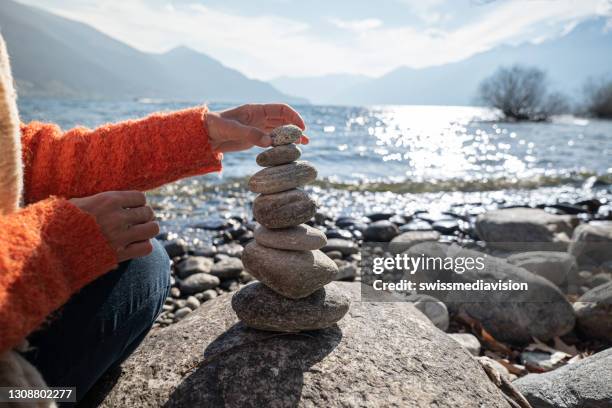 detalle de la persona apilando rocas junto al lago - farallón fotografías e imágenes de stock