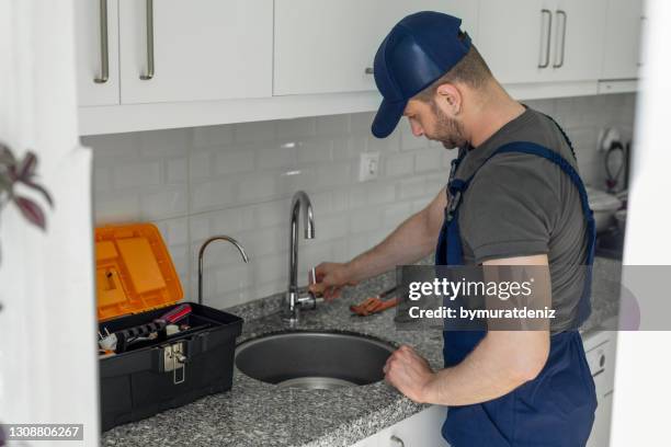 young worker control to faucet in kitchen - water plug stock pictures, royalty-free photos & images