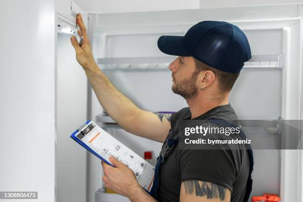 young technician checking refrigerator - refrigerator stock pictures, royalty-free photos & images