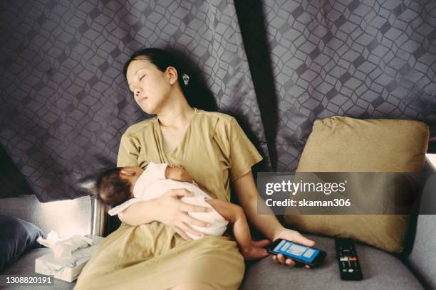 young adult  asian mother is feeding daughter and feeling exhausted at home - moms crying in bed stockfoto's en -beelden