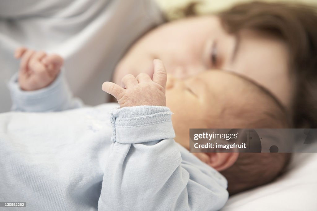 Mother and four-week-old infant laying on a child bed