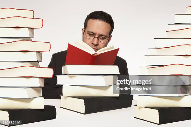 man surrounded by stacks of books reading a book - surrounding ストックフォトと画像