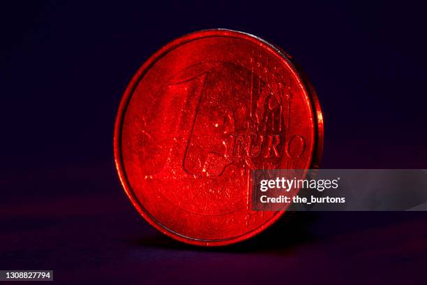 close-up of red lighted one euro coin on black background - european union coin stock pictures, royalty-free photos & images