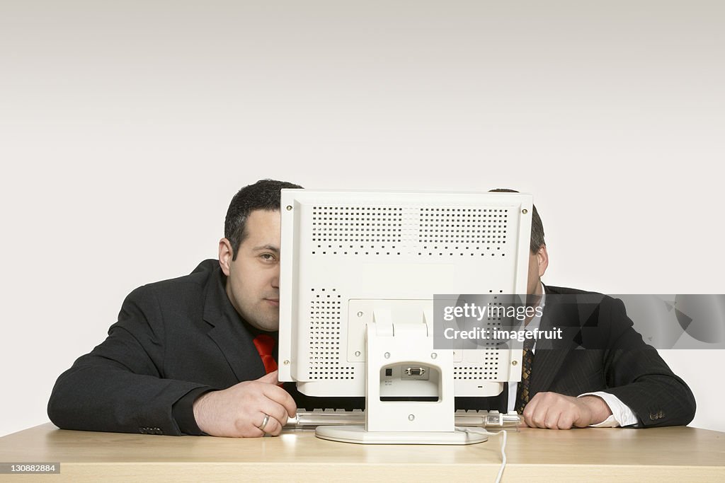 Two businessmen sitting behind a computer monitor