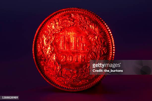 close-up of red lighted one swiss franc coin on black background - franken stockfoto's en -beelden