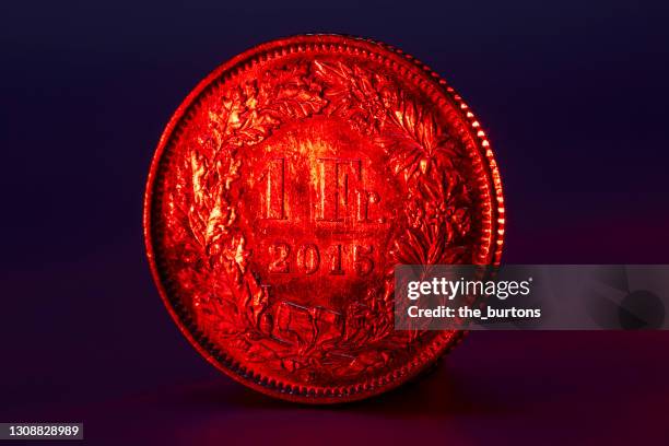 close-up of red lighted one swiss franc coin on black background - recessed lighting 個照片及圖片檔