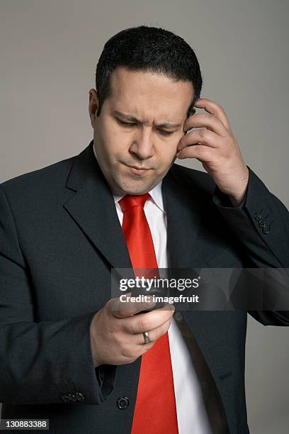 man gazing thoughtfully at the screen of his pocket pc - knitting brow stock pictures, royalty-free photos & images