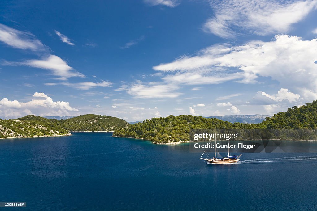 Sailing boat motors passing an island group, Mljet Island, Mljet National Park, Dubrovnik-Neretva, Dalmatia, Croatia, Europe