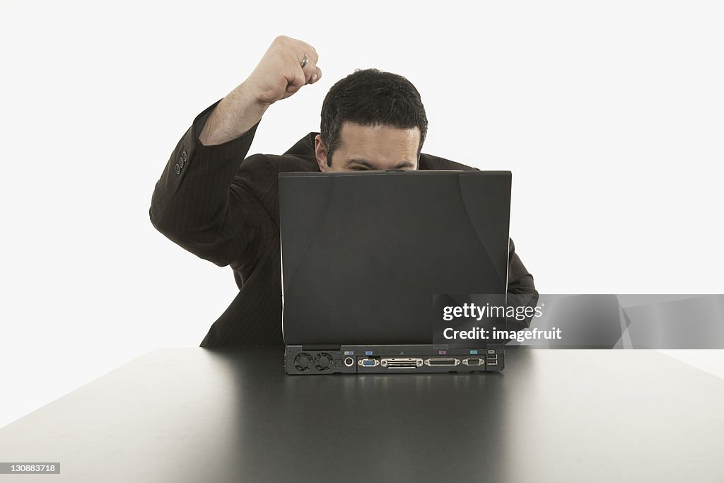 Businessman sitting in front of his laptop, angry