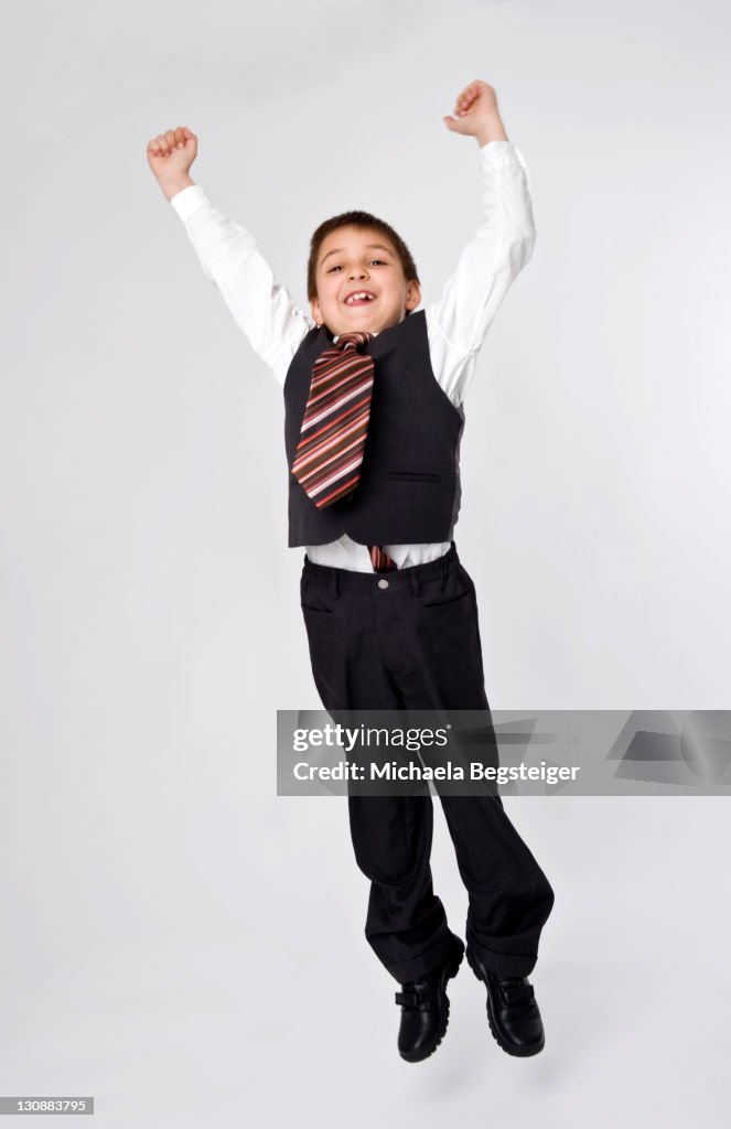 Boy, 8, dressed as a businessman, jumping