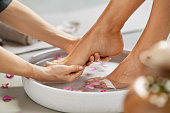 Beautician washing woman feet for pedicure treatment