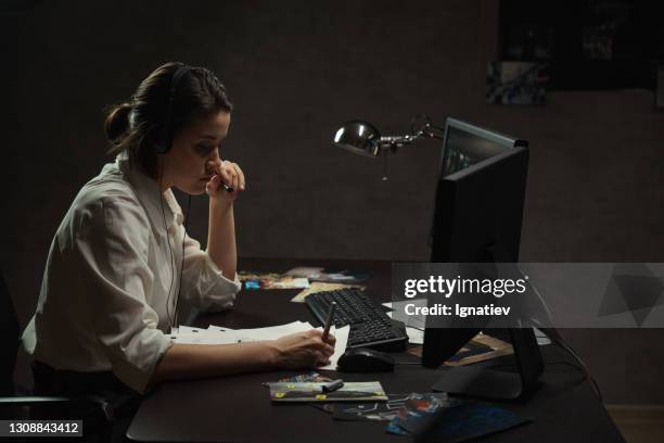 a woman frowns, trying to hear the soft sound in the headset - female fbi stock pictures, royalty-free photos & images