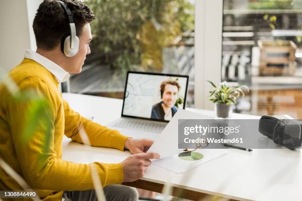 businessman explaining document while attending business meeting through video conference at home office - two people video conferencing stock pictures, royalty-free photos & images