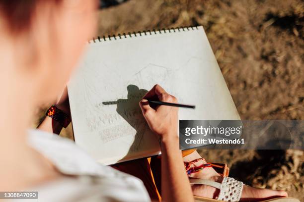 young woman artist drawing in spiral notebook - sketch pad fotografías e imágenes de stock