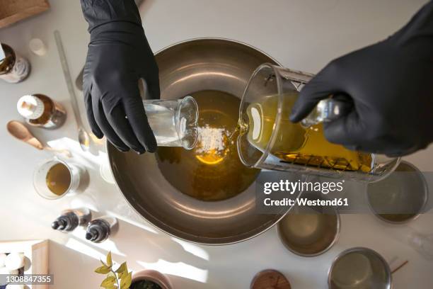 woman mixing ingredients in steel bowl while making soap in workshop - seife stock-fotos und bilder
