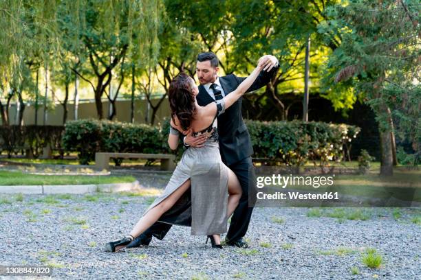 flexible female practicing with male dancer in public park - evening wear stock pictures, royalty-free photos & images