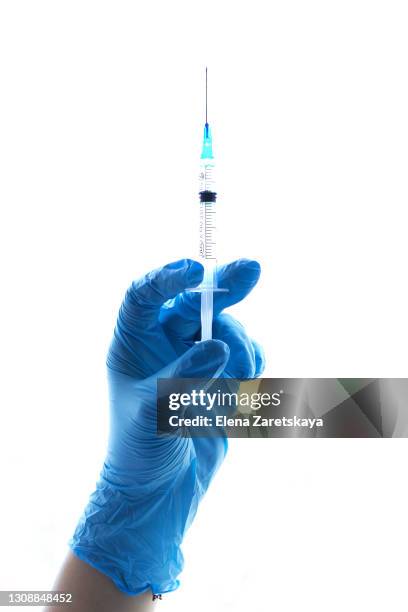 a close-up view of a healthcare worker in personal protective equipment holding a medical syringe on a white background - stock photo - aguja fotografías e imágenes de stock