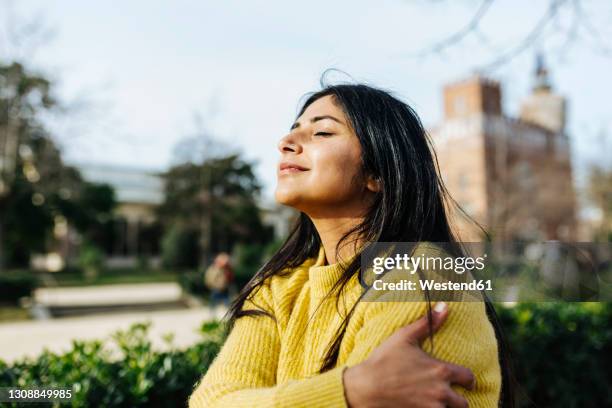 smiling woman hugging self against sky in public park - krama sig själv bildbanksfoton och bilder