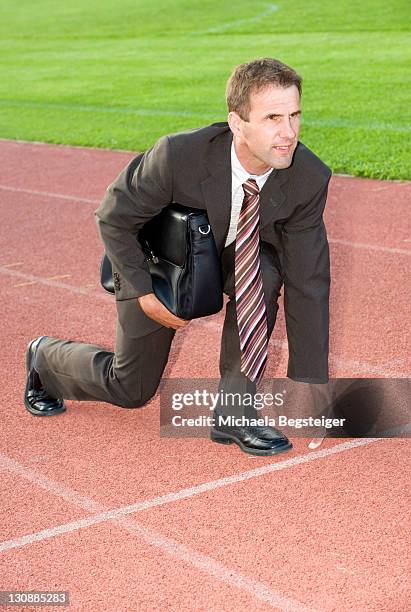 businessman at starting line of a running track, symbolic of carreer start of a running track, symbolic of carreer start - necktie run stockfoto's en -beelden