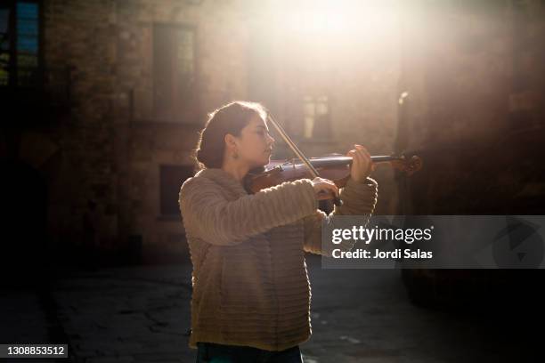 woman playing violin on street - busker stockfoto's en -beelden