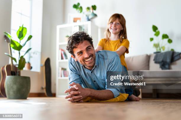 father and cute redheaded daughter having fun together at home - small child sitting on floor stockfoto's en -beelden