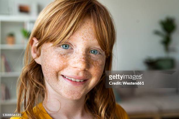 smiling redhead girl with blue eyes at home - freckle girl stock pictures, royalty-free photos & images