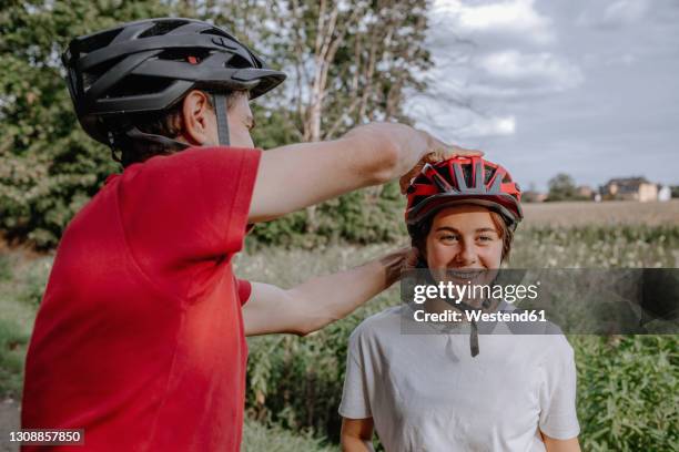father helping daughter wearing cycling helmet - bicycle daughter stock-fotos und bilder