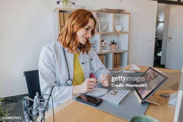 doctor listening to patient on video call over digital tablet while sitting at office - telemedicine stock pictures, royalty-free photos & images
