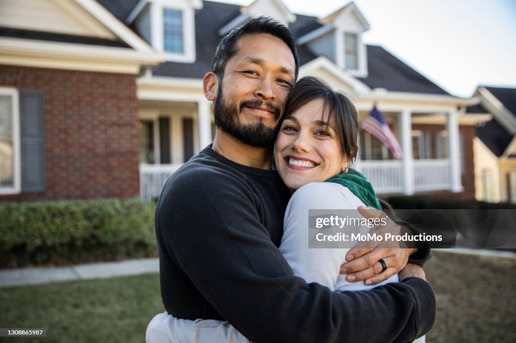 Husband and wife embracing in front of home