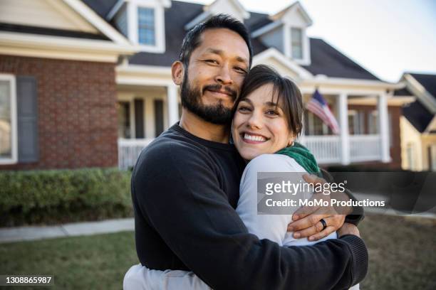 husband and wife embracing in front of home - couple stock pictures, royalty-free photos & images