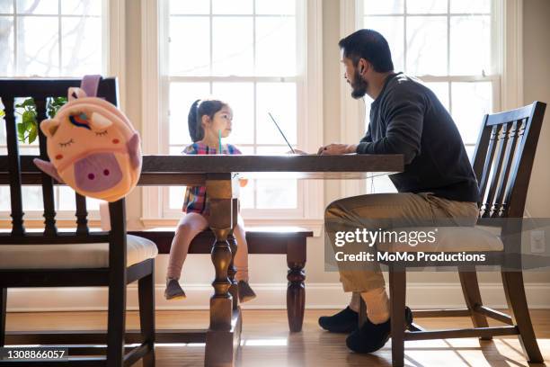 father working from home and helping daughter with schoolwork - athens photos et images de collection