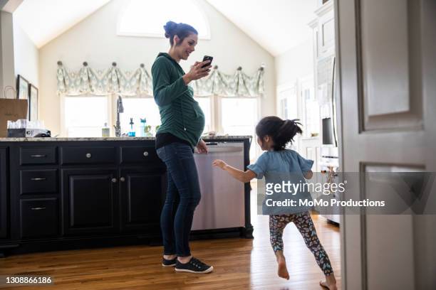 pregnant woman using smartphone at home - girls in leggings stock-fotos und bilder