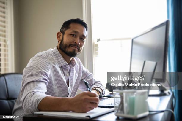 man working on laptop in home office - asian man looking up stock pictures, royalty-free photos & images