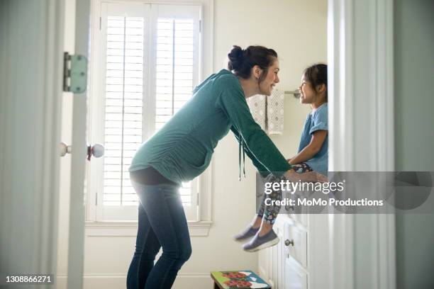 mother talking to daughter on bathroom counter - chinese family taking photo at home stock-fotos und bilder