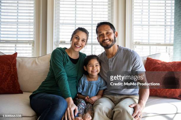 portrait of family at home on sofa - multiracial person stock pictures, royalty-free photos & images