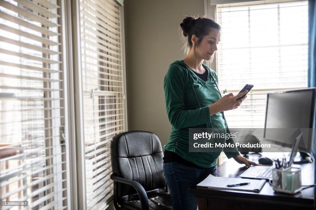 Pregnant woman using smartphone in home office