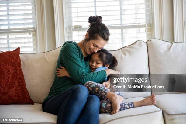 mother and daughter snuggling on sofa - child mental health wellness stock-fotos und bilder