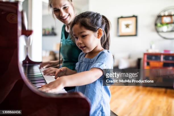 mother and daughter playing piano - de descendencia mixta fotografías e imágenes de stock